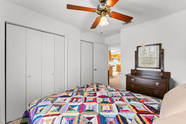 bedroom featuring carpet floors, visible vents, multiple closets, and a ceiling fan