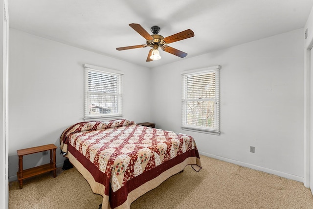 bedroom featuring a ceiling fan, light colored carpet, multiple windows, and baseboards