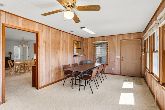 dining area with wooden walls, light colored carpet, crown molding, and visible vents