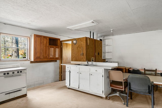 kitchen with light countertops, concrete floors, concrete block wall, and white cabinets