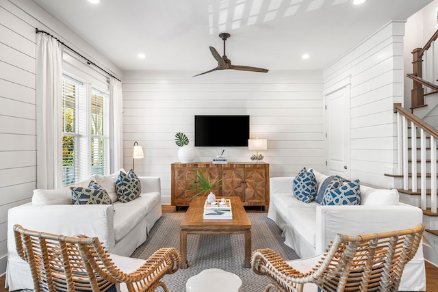 living area with ceiling fan, wooden walls, stairway, and recessed lighting