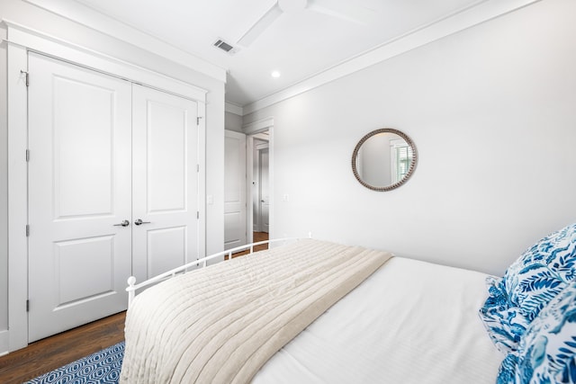 bedroom featuring a ceiling fan, visible vents, a closet, dark wood-style floors, and crown molding