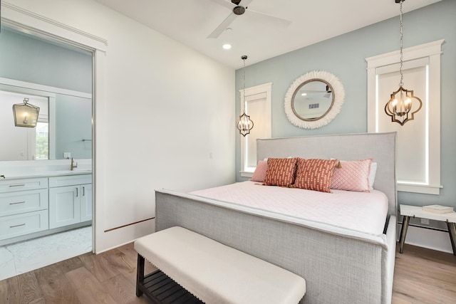 bedroom with a sink, ensuite bath, wood finished floors, and recessed lighting