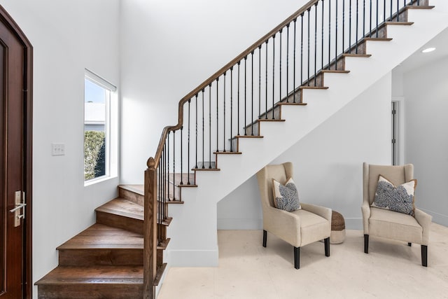 stairs featuring a high ceiling and baseboards