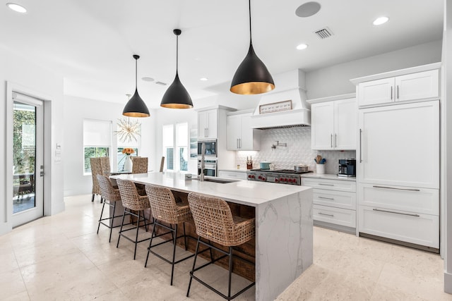 kitchen with visible vents, a spacious island, custom range hood, appliances with stainless steel finishes, and backsplash