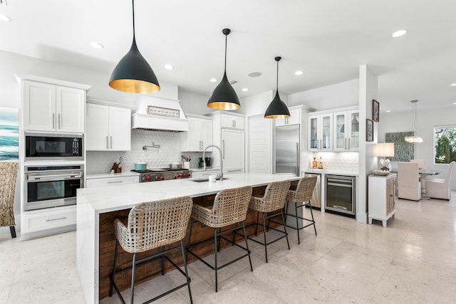 kitchen with built in appliances, beverage cooler, a sink, white cabinetry, and backsplash