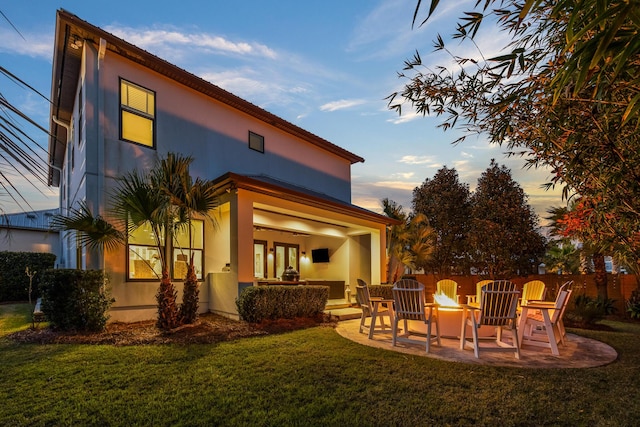 rear view of property featuring stucco siding, a patio, and a lawn