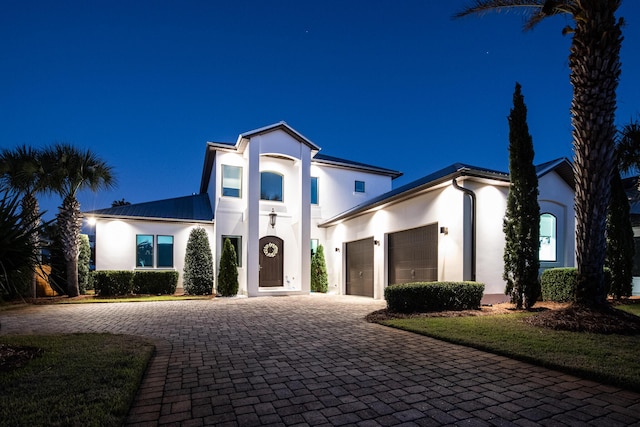 view of front of home with an attached garage, decorative driveway, and stucco siding