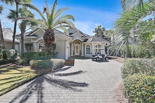 mediterranean / spanish home featuring a tile roof and stucco siding