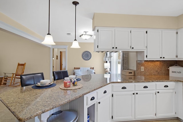 8840 Sand Pine Dr, Navarre, FL 32566 - kitchen featuring light stone countertops, a peninsula, visible vents, white cabinets, and decorative backsplash