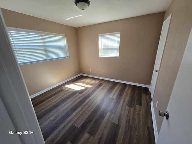 unfurnished bedroom with baseboards and dark wood-type flooring