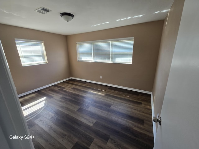 spare room with dark wood-style floors, baseboards, and visible vents