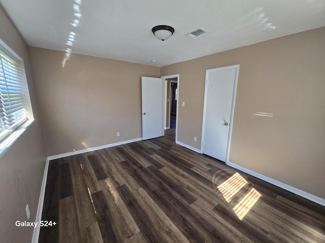 unfurnished bedroom featuring baseboards, visible vents, and dark wood-style flooring