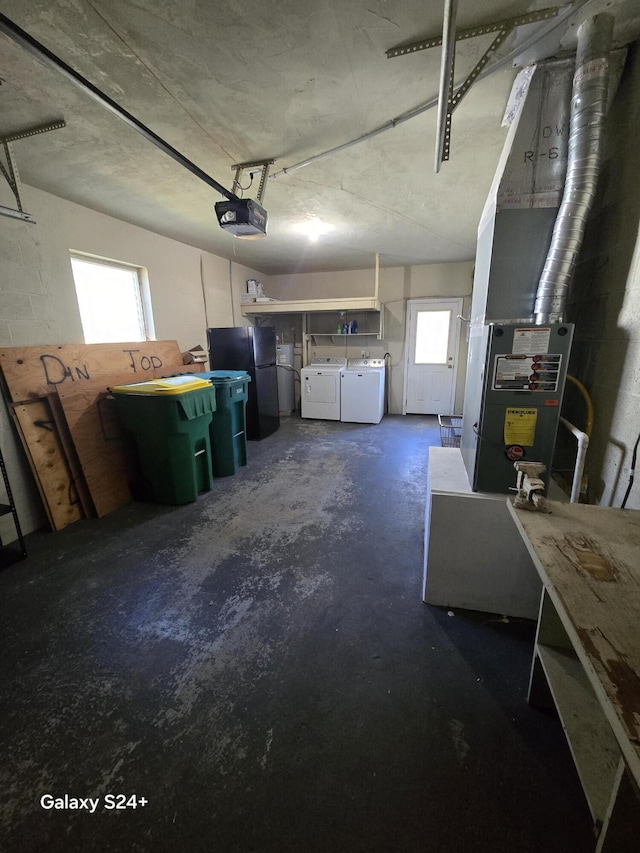 garage featuring a garage door opener, freestanding refrigerator, and washing machine and clothes dryer