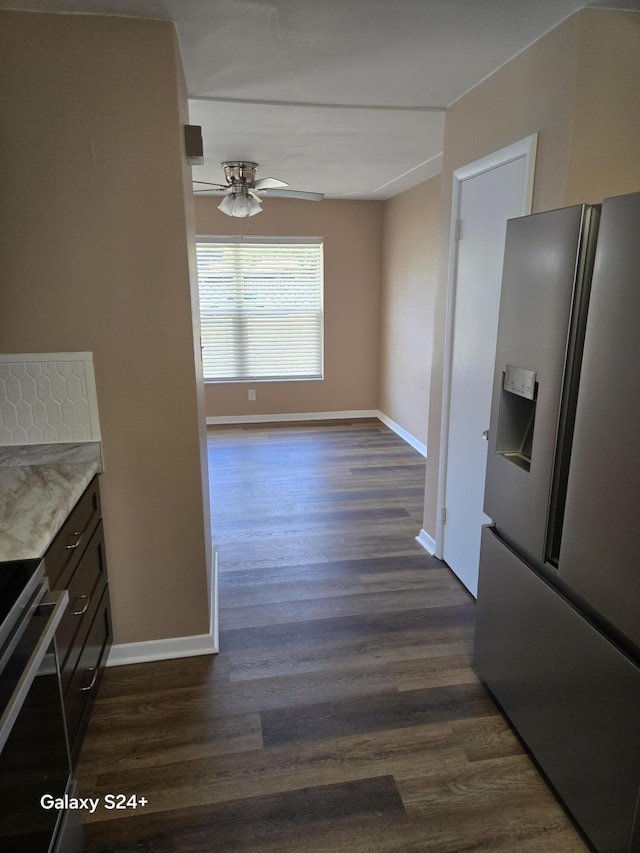 kitchen featuring dark wood finished floors, stainless steel fridge with ice dispenser, a ceiling fan, range, and baseboards