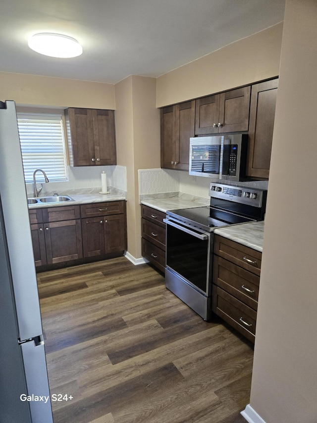 kitchen with dark brown cabinetry, dark wood-style floors, appliances with stainless steel finishes, and a sink