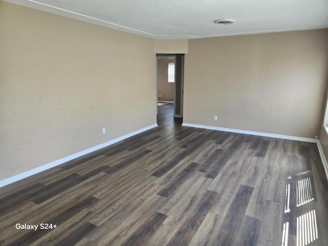 unfurnished room featuring visible vents, baseboards, and dark wood-style flooring