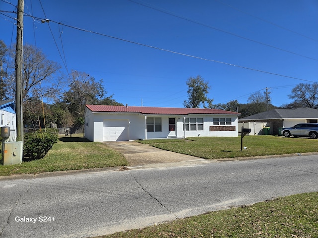 ranch-style house with metal roof, a garage, driveway, stucco siding, and a front yard