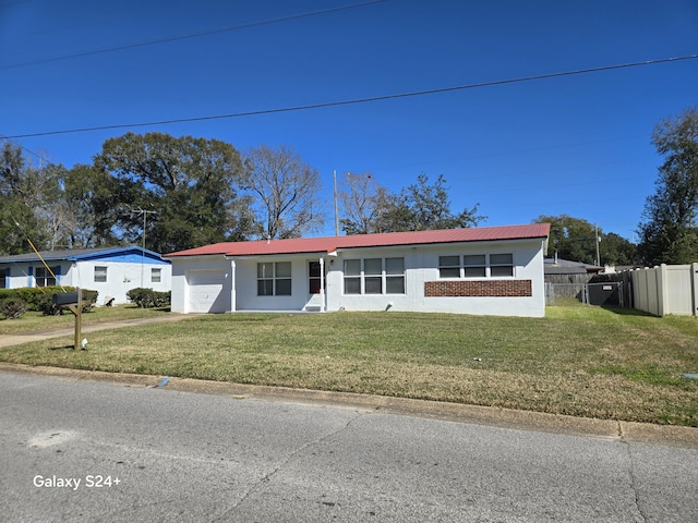 view of front of home with metal roof, an attached garage, brick siding, fence, and a front yard