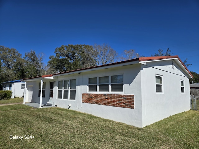 view of front facade with a front yard, brick siding, and stucco siding