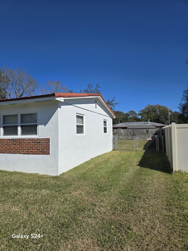 view of home's exterior featuring stucco siding, a yard, and fence