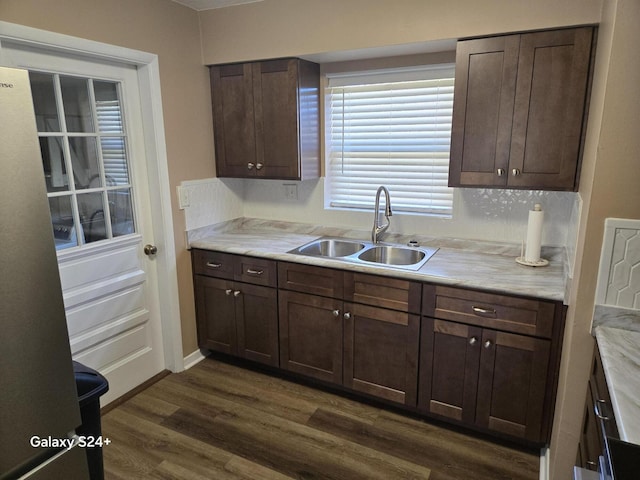 kitchen with a sink, baseboards, light countertops, dark brown cabinets, and dark wood-style floors