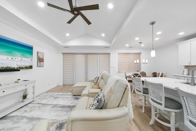 living area featuring recessed lighting, a raised ceiling, ceiling fan with notable chandelier, and light wood-style flooring