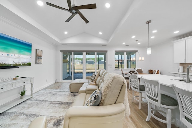 living area featuring recessed lighting, ceiling fan with notable chandelier, light wood-style floors, and vaulted ceiling