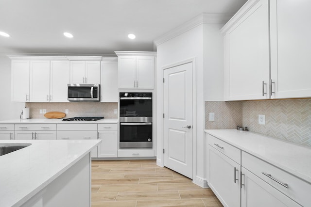 kitchen with white cabinetry, appliances with stainless steel finishes, light countertops, and decorative backsplash