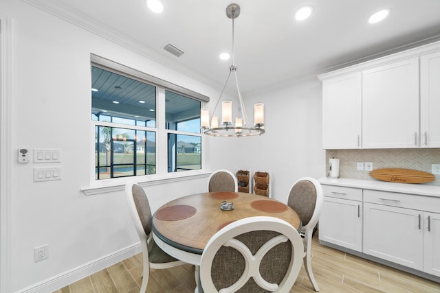 dining room featuring a chandelier, ornamental molding, and light wood-style floors