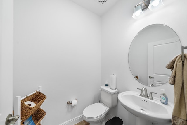 bathroom with baseboards, toilet, and a sink