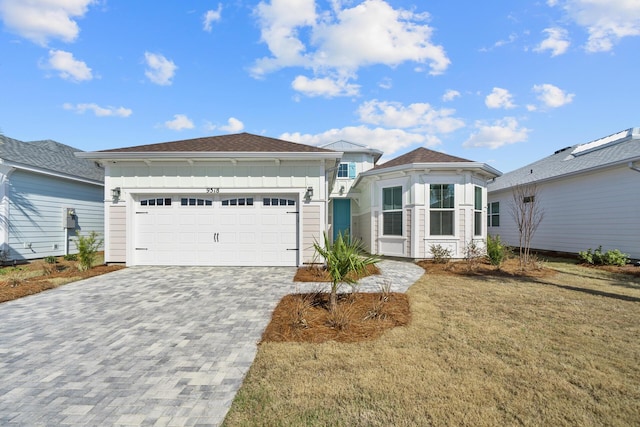 single story home with a garage, board and batten siding, decorative driveway, and a front yard
