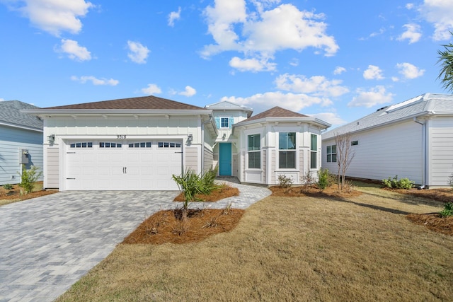 view of front of home featuring a front lawn, decorative driveway, and an attached garage