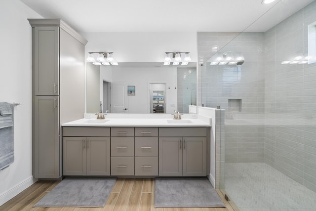 ensuite bathroom with wood finished floors, walk in shower, double vanity, and a sink