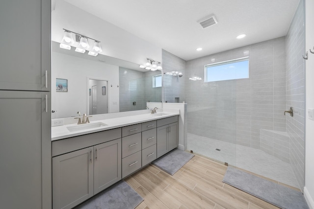 full bath with walk in shower, double vanity, a sink, and wood finished floors