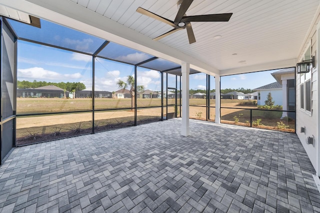 unfurnished sunroom featuring a ceiling fan and a residential view