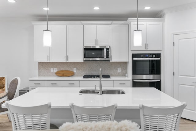 kitchen with double wall oven, light countertops, crown molding, and stainless steel microwave