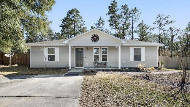 view of front of home with a shingled roof, covered porch, and fence