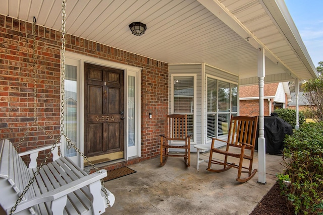 property entrance with a porch and brick siding