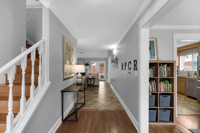 hall featuring crown molding, stairway, a sink, wood finished floors, and baseboards