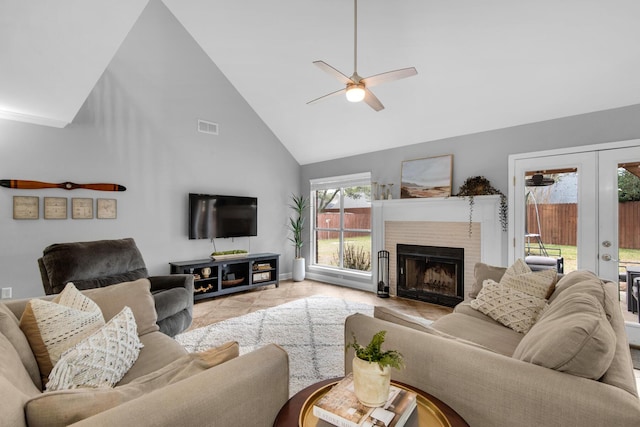 living area with french doors, visible vents, a ceiling fan, a brick fireplace, and high vaulted ceiling