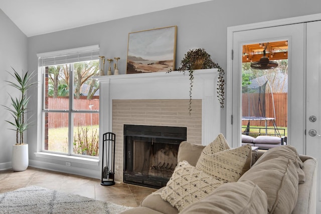 tiled living area featuring baseboards, a fireplace, and a healthy amount of sunlight