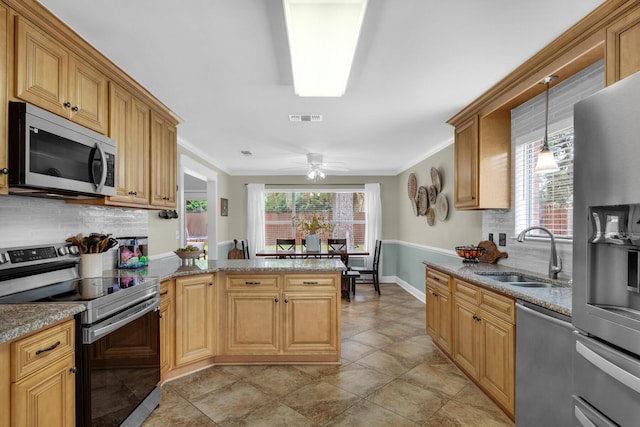 kitchen featuring visible vents, appliances with stainless steel finishes, a peninsula, a sink, and backsplash