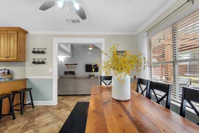 dining space with ceiling fan, baseboards, visible vents, and crown molding