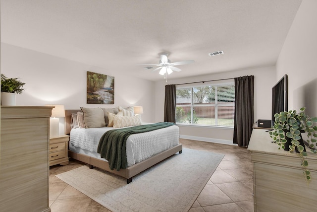 bedroom featuring a ceiling fan, visible vents, baseboards, and light tile patterned floors