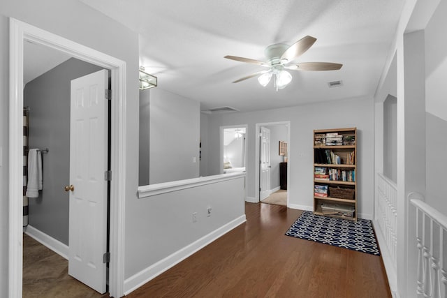 hallway with visible vents, baseboards, and wood finished floors