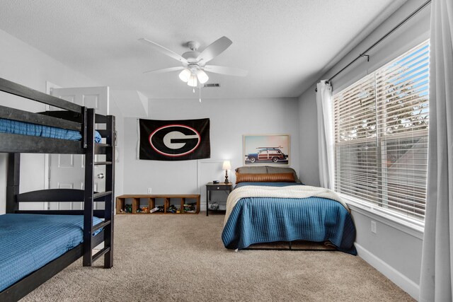 carpeted bedroom with a ceiling fan, baseboards, visible vents, and a textured ceiling