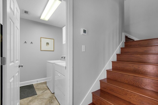 stairs with separate washer and dryer, visible vents, and baseboards