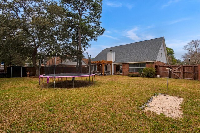 rear view of house featuring a trampoline, a gate, and a fenced backyard