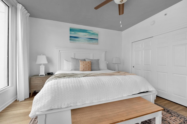 bedroom featuring light wood-type flooring, a ceiling fan, and a closet